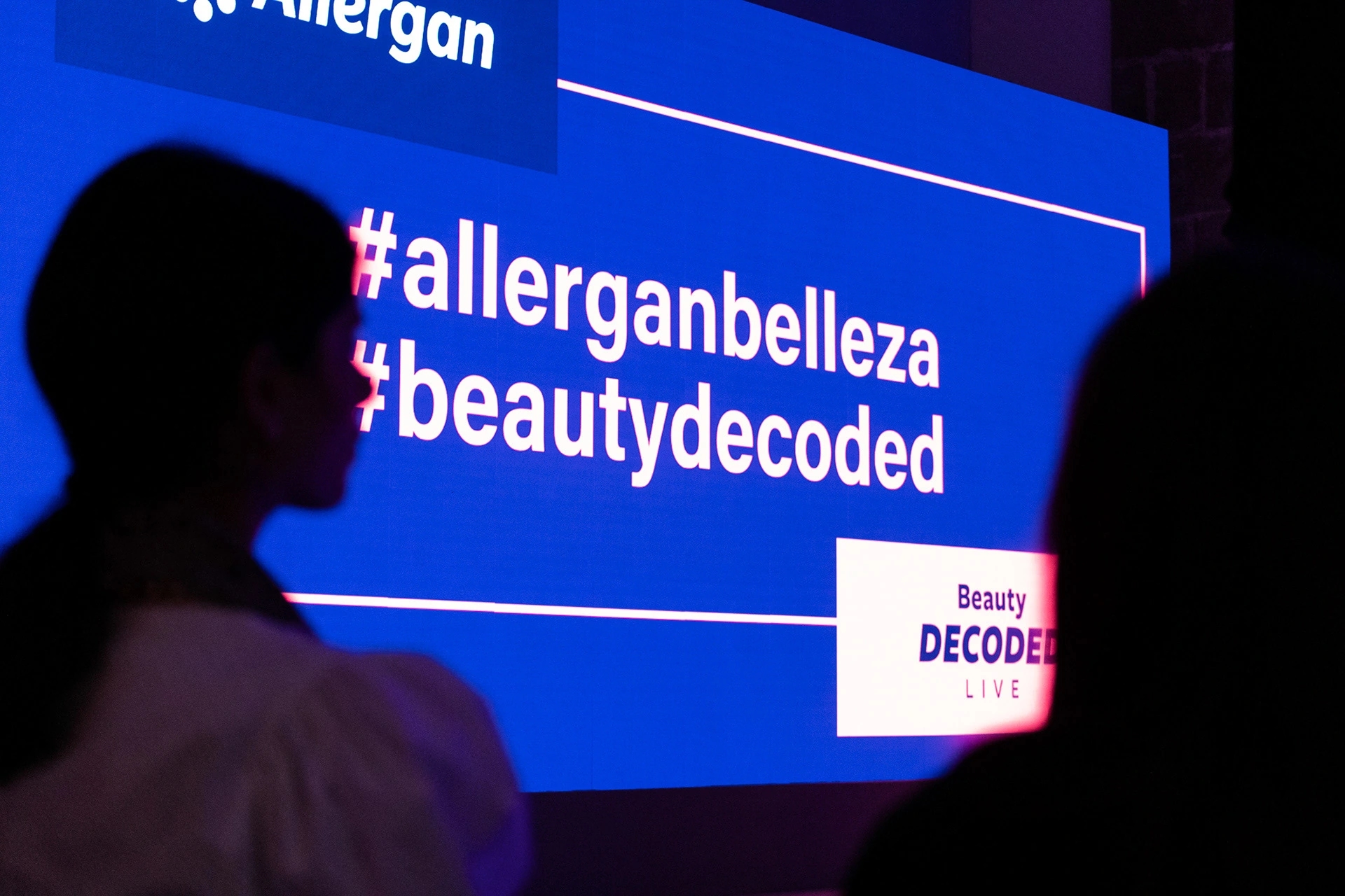 Fotografía de evento para Vogue España y Allergan Belleza con influencers top en colaboración con Condé Nast. Pantalla con el nombre del evento en azul.