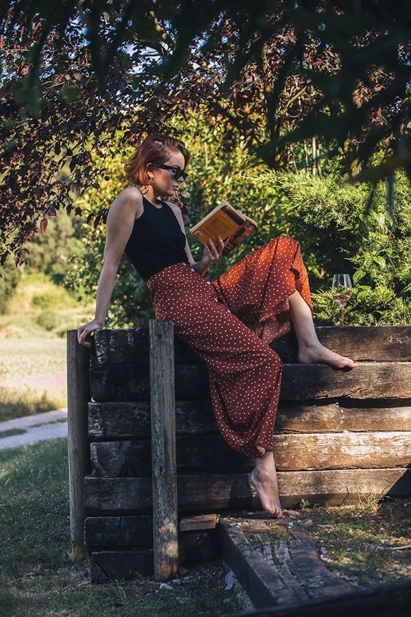 Mujer lee libro Mujeres con copas de vino y botella de Viña Esmeralda mediterranean al atardecer con luz espectacular en la piscina.