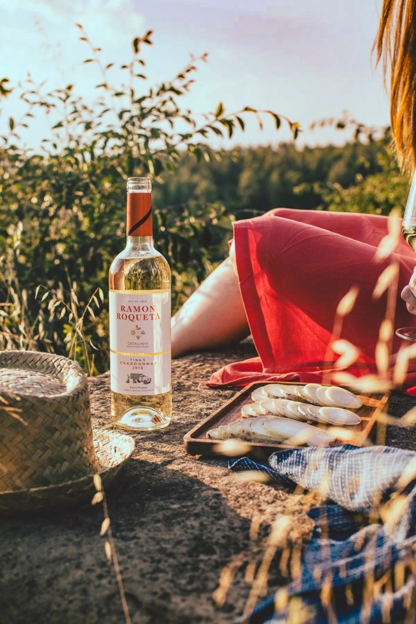 Mujer disfrutando de vino blanco y queso en el viñedo de las bodegas Ramon Roqueta en DO Bages, Cataluña al atardecer.