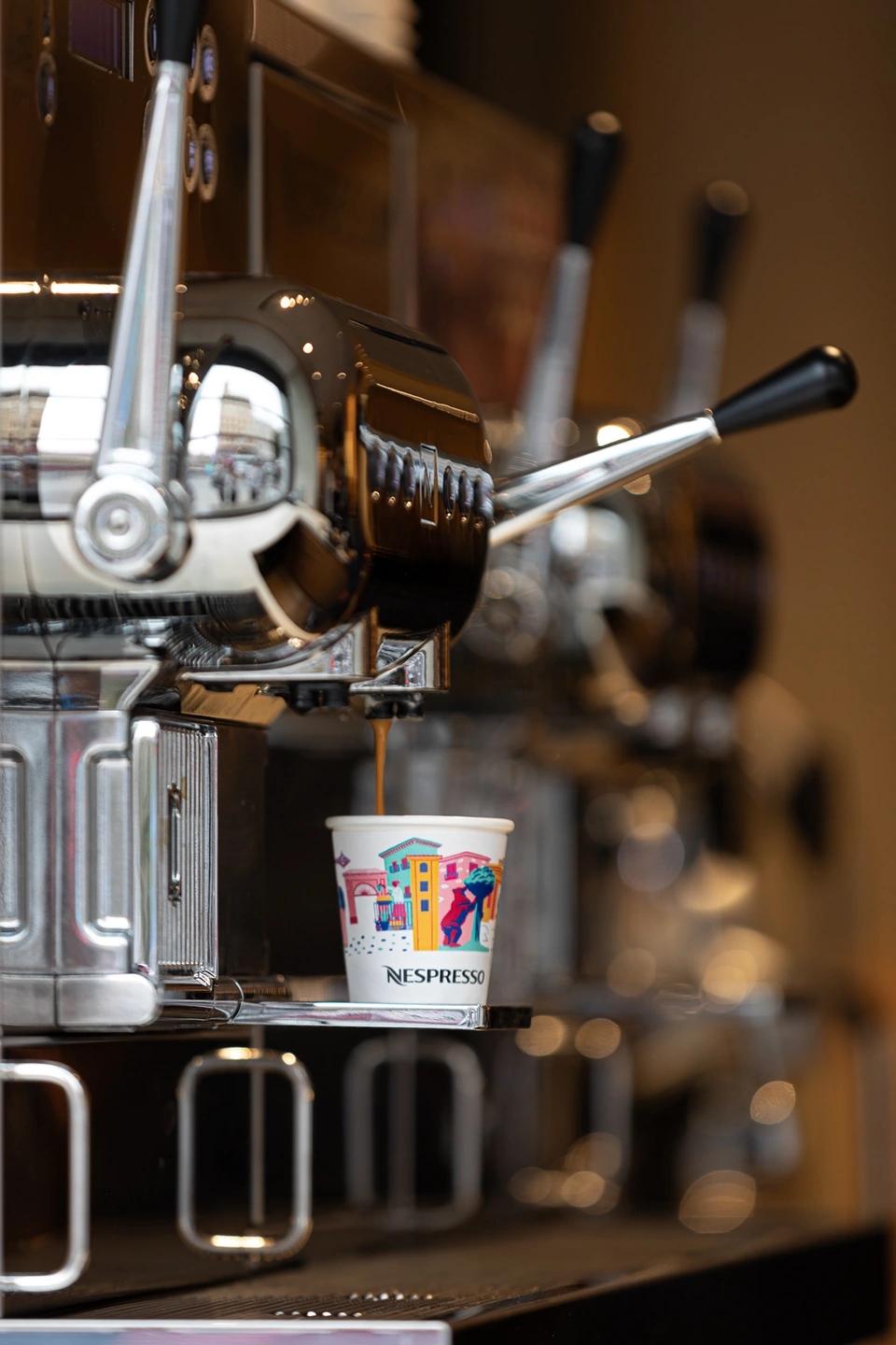 Maquina de café profesional nespresso haciendo un café con leche de la marca. Máquina plateada profesional de barista.