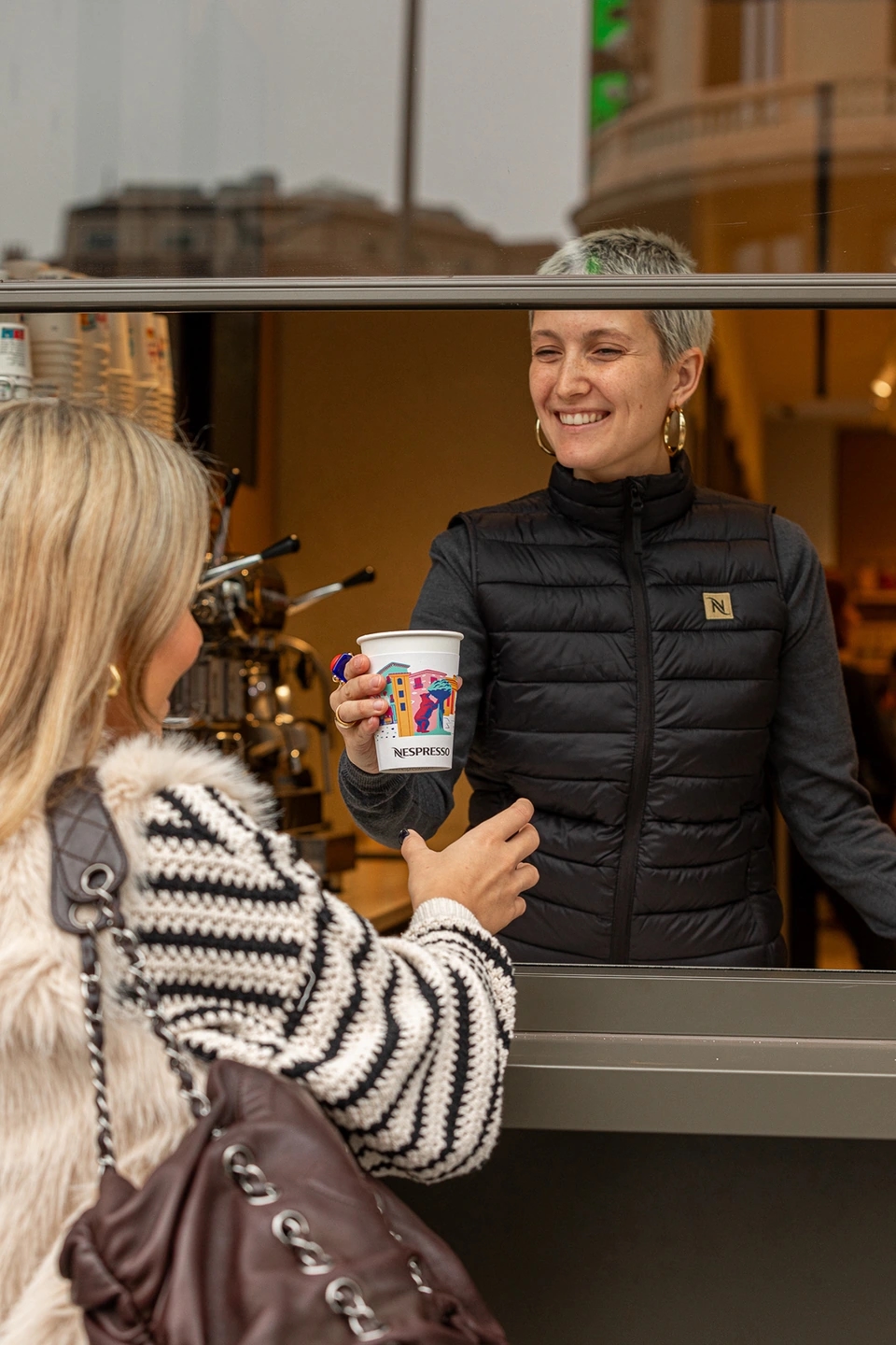 Bartender sirviendo café a una mujer rubia en la tienda Nespresso gran vía de Madrid